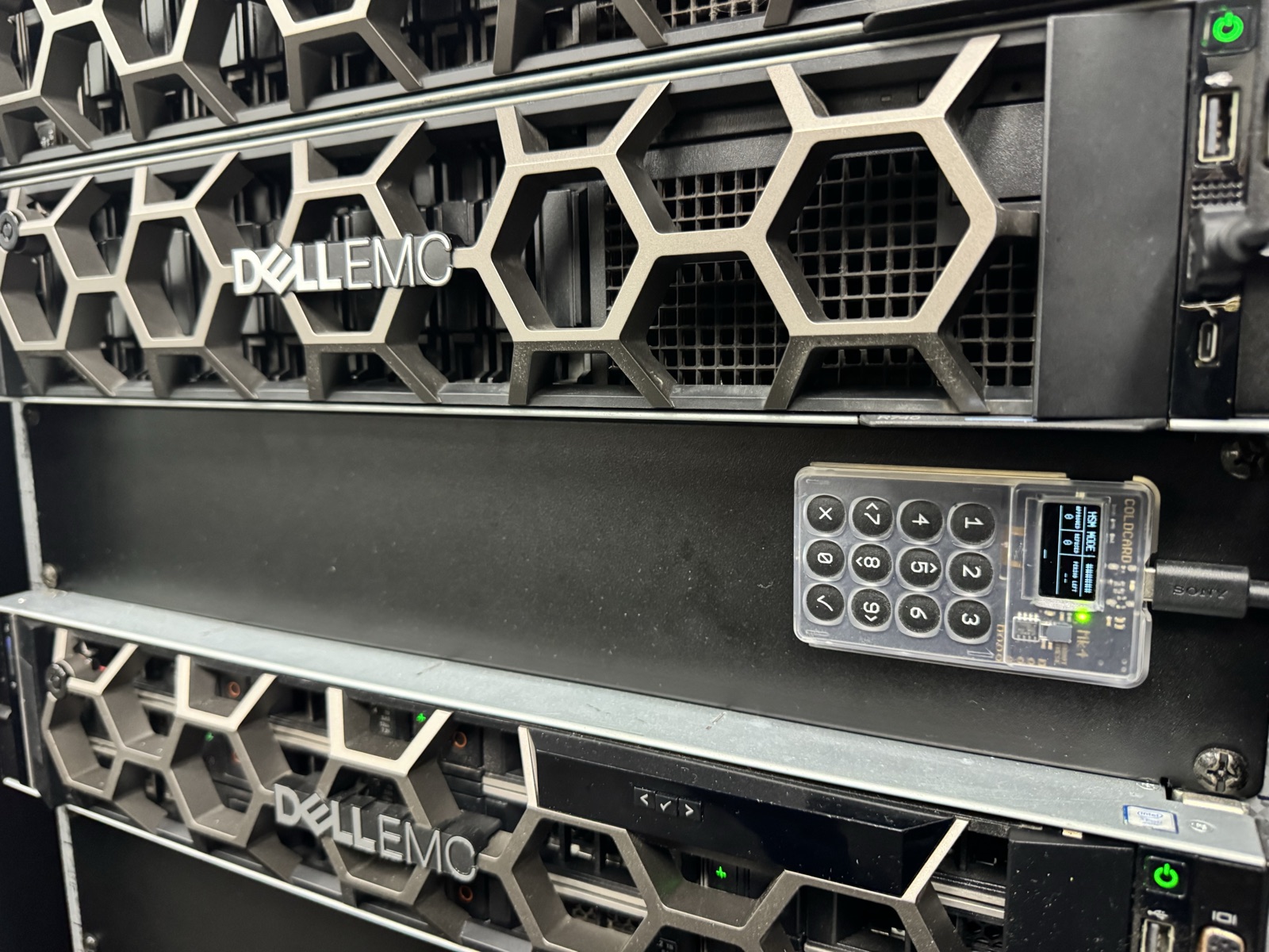 A Coldcard in HSM mode plugged into a host between rack-mounted servers